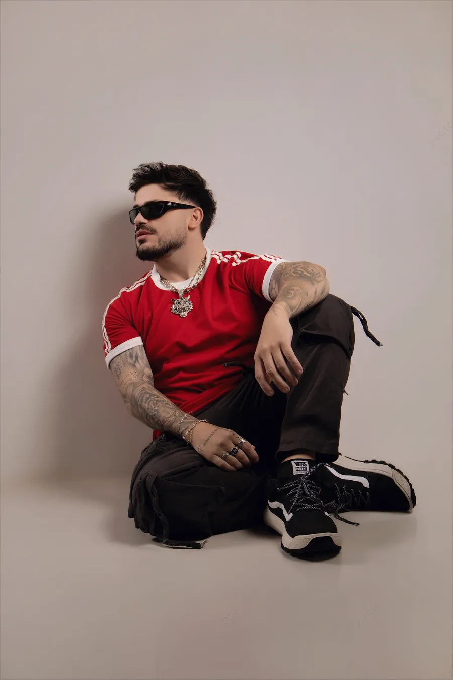 DJ Toledo sentado no chão de camiseta vermelha