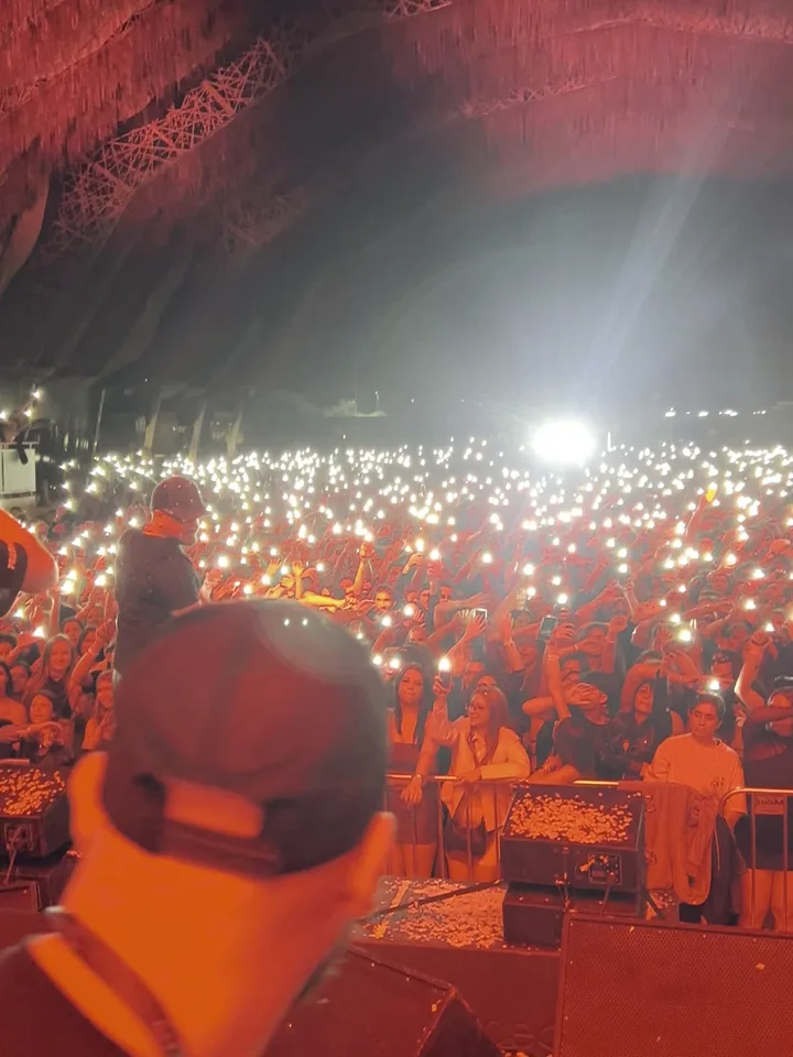 DJ Toledo de costas, diante da plateia com as luzes vermelhas