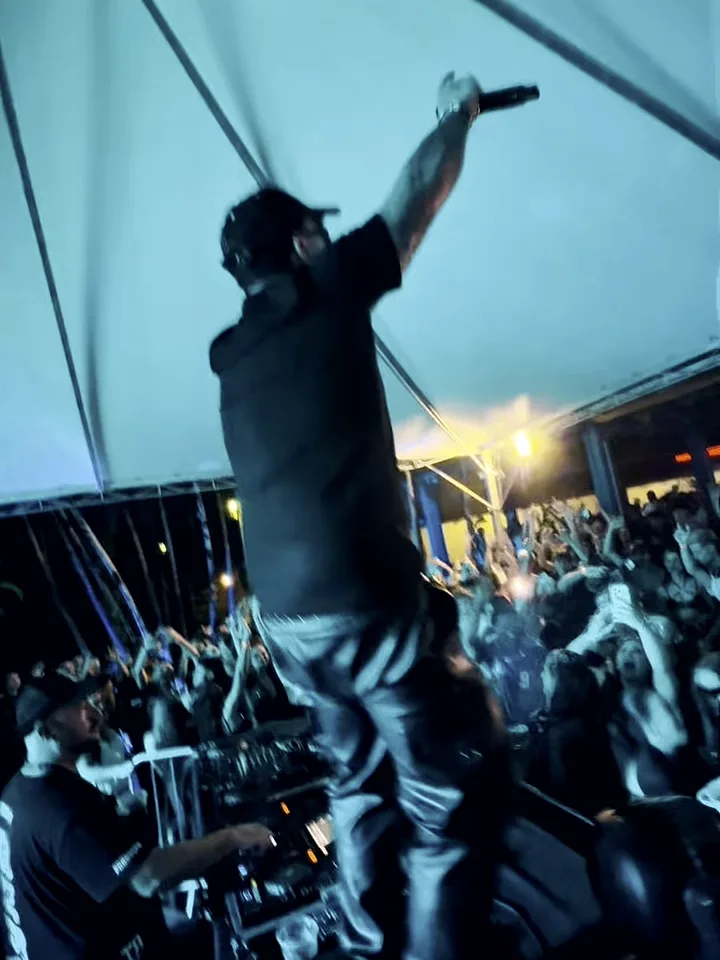 DJ Toledo de braço erguido em cima da mesa, comandando a pista